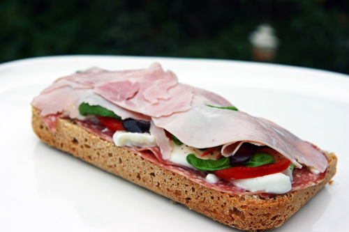 Sandwich med skinke, salami, mozarella, tomater, basilikum, oliven og olivenolie